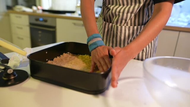Young woman assembling crust on work surface in kitchen