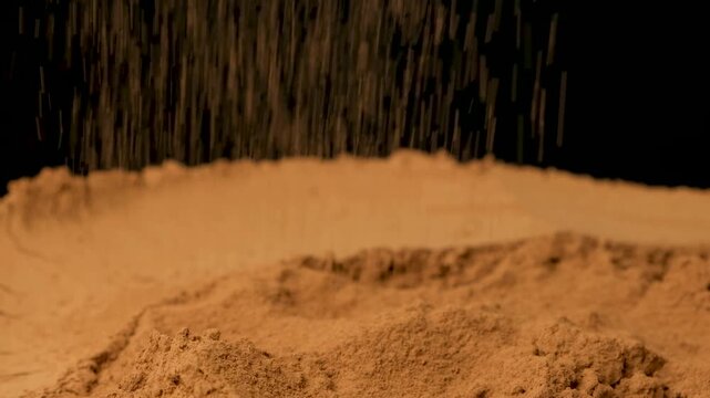 Cinematic sprinkle of raw cocoa powder on black background slow motion