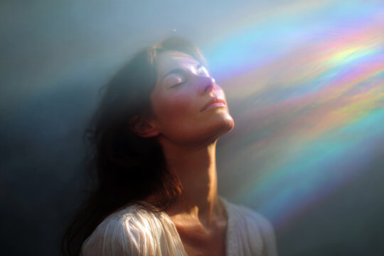 Woman inhaling soft rainbow light across face for breathwork portrait and calming background for wellness design