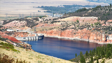 Obraz premium Bighorn Dam spans a narrow canyon above deep blue reservoir waters, highlighting water management infrastructure amid the rugged landscapes of the American West.