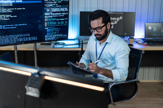 Idian system analyst uses writing on digital tablet to design database architecture or review complex backend source code flow chart inside security network office