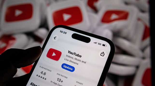 Closeup of a smartphone screen showing the youtube app update page on the app store, with a background of multiple youtube logo icons