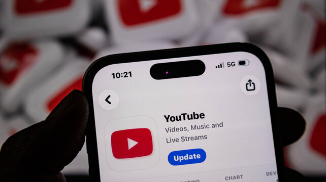 Closeup of a smartphone screen showing the youtube app update page in the app store, with a blurred youtube logo background