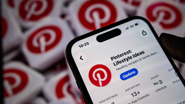 Closeup of a smartphone screen displaying the pinterest app store page with an update button, set against a background of multiple pinterest app icons