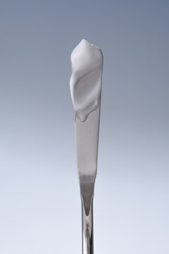 applying sunscreen, cream on a spatula, spf cream swatch, white cream smear, cosmetic textures,  skincare product sample