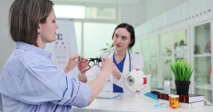 Woman doctor gives phoropter to patient during examination in clinic. Ophthalmologist uses special tool to test lady eyesight in hospital slow motion