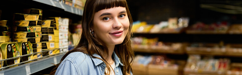 Obraz premium Young woman enjoys a delightful shopping experience in a vibrant supermarket aisle