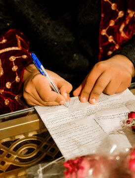 Hands of a bride writing on paper during a traditional wedding ceremony with ceremony tradition marriage pakistani feminine