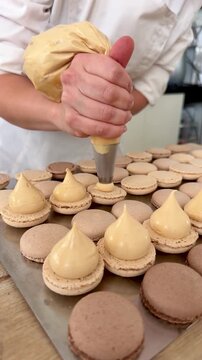 Pastry chef filling French macarons with salted caramel ganache