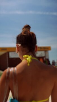 Woman in bikini walking along a sunny beach