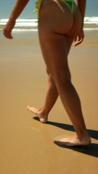 Woman walking along a sunny beach by the ocean