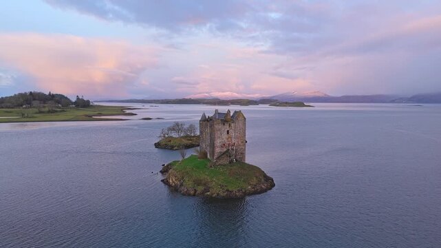 Aerial view flying over castle stalker at sunrise
