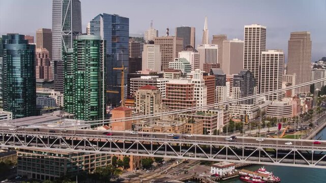 High-angle daytime shot of vehicles crossing the Bay Bridge with downtown skyscrapers in the background.