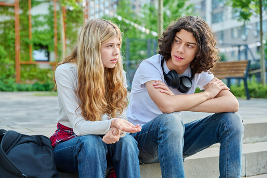 Sad teenage girl talking to friend on street stairs
