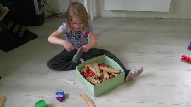 Child puts the toys in the box to establish order. Kid 5 years old establish order. Caucasian little girl tidying. The toddler baby himself cleans up, collects toys in the nursery after game playing.