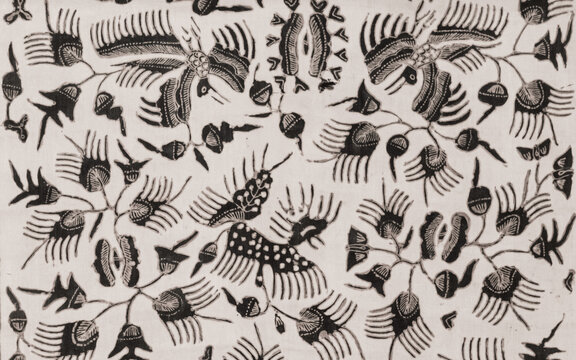 Traditional Indonesian batik tulis fabric pattern background. Detailed view of vintage monochrome hand-painted textile ornament featuring stylized birds, wings, and floral motifs on white cloth.