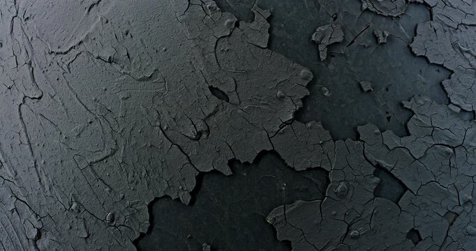 Dark peeling cracked texture slow rotation. Close-up of rough dark surface with thick cracked layers and peeling flakes. Smooth continuous rotation reveals evolving light reflections.