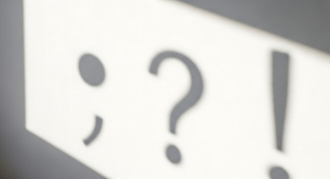 White surface displaying punctuation marks including semicolon, question mark, and exclamation mark in shallow depth.