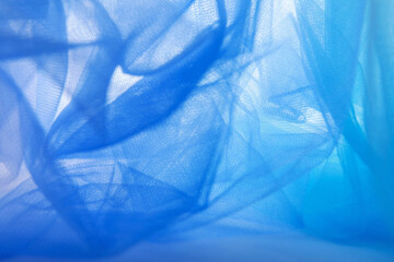 Obraz premium Background, abstract blue mesh fabric creates soft wavy folds.