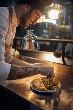 Cook in Professional Modern  kitchen, restaurant concept. chef finishing meal serving with precision.
