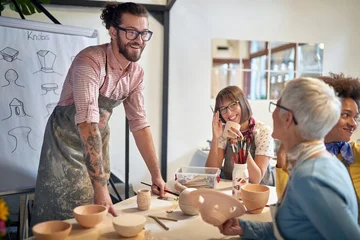 smiling group of people making pots from clay at a pottery studio. Creative, hobby ,activities concept © luckybusiness