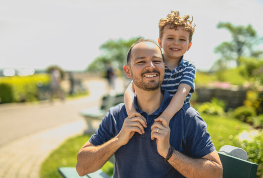 man playing with his son outdoors in park place