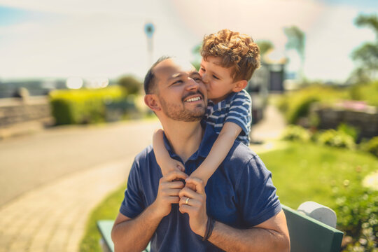 man playing with his son outdoors in park place