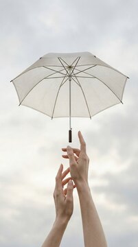 Hands holding transparent umbrella on cloudy sky