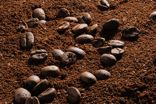 High-Resolution close-up of roasted coffee beans rolling on coarse ground powder extreme detail ultra sharp maximum sharpness