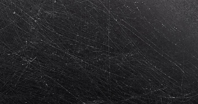Dark scratched texture. Close-up view of a matte black surface with dense fine scratches and subtle wear marks. Smooth continuous rotation reveals evolving light reflections.