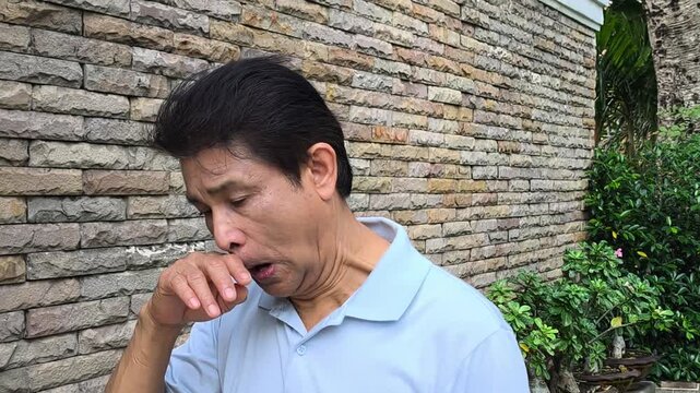 Sick old Asian senior man catching a cold or flu, suffering from runny nose