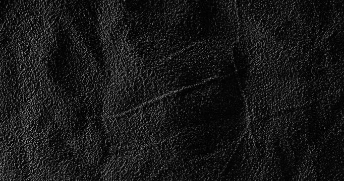 Dark crumpled texture surface rotating. A black, rough, wrinkled paper surface, moving slowly. Used as a background and texture.