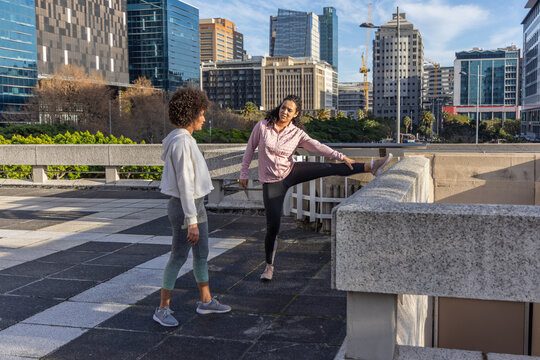 Urban rooftop plaza is hosting stretching session on patterned tiled surface near concrete parapet