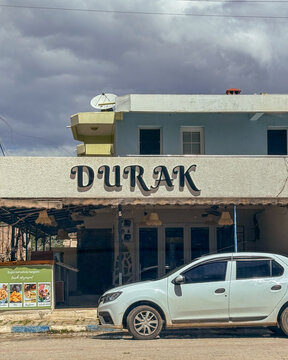 Durak shop facade with parked car under moody clouds in Antalya for travel editorial urban lifestyle architecture blogs and social media, 5 May 2026 Antalya, Turkey