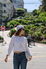 Fototapeta premium Woman walking near the curving flower lined road of Lombard Street in San Francisco
