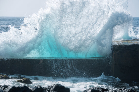Explosive Atlantic wave impacts the volcanic seawall of Piscina Natural Mesa del Mar in Tacoronte, Tenerife, sending turquoise water and white foam high into the air