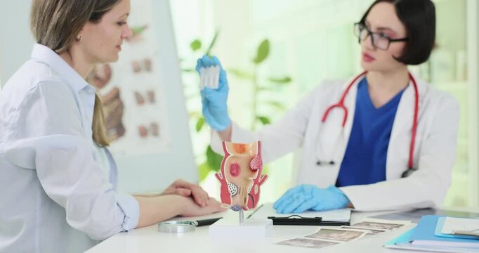 Human rectum model against doctor giving suppositories to patient in hospital. Woman visits proctologist to cure hemorrhoids in clinic slow motion