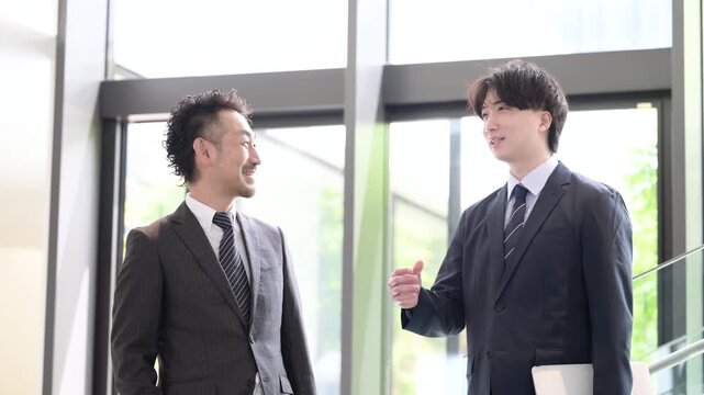 新緑のオフィスの窓際で会話する若手ビジネスマンと上司、取引先のコミュニケーションなどの仕事イメージの動画