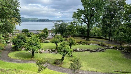 錦江湾を望む世界文化遺産・仙巌園の美しい日本庭園と曲水の庭、緑豊かな芝生と歴史ある大名庭園の自然風景、鹿児島県の観光名所。 © Elsie