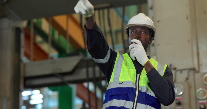Factory supervisor directing production team with walkie-talkie