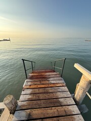 Obraz premium a staircase at the end of the wooden pier leads into the sea
