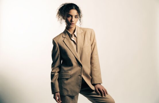Studio portrait of a confident young woman in a stylish beige suit