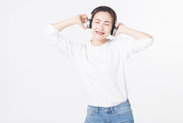 Fototapeta premium Happy young woman listening to music with headphones on light background