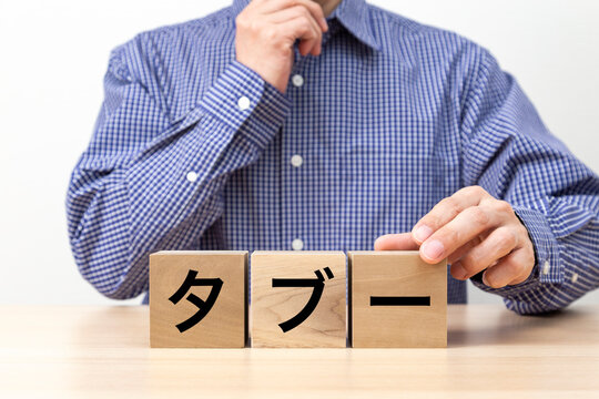 「タブー」と書かれたブロックと男性