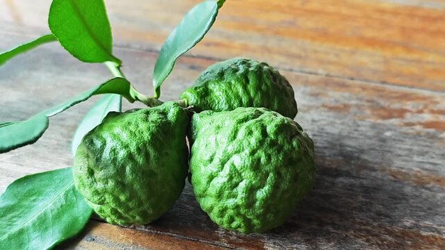 Fresh kaffir lime fruits with leaves on wooden table background.