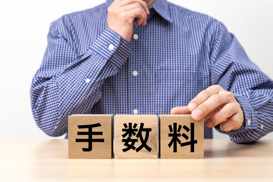 「手数料」と書かれたブロックと男性