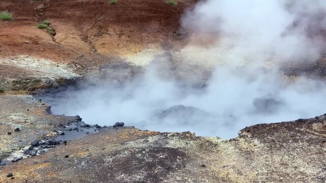 Boiling mud pot and hot spring emitting thick steam in the Seltun geothermal area in Krysuvik. Volcanic landscape on Reykjanes Peninsula