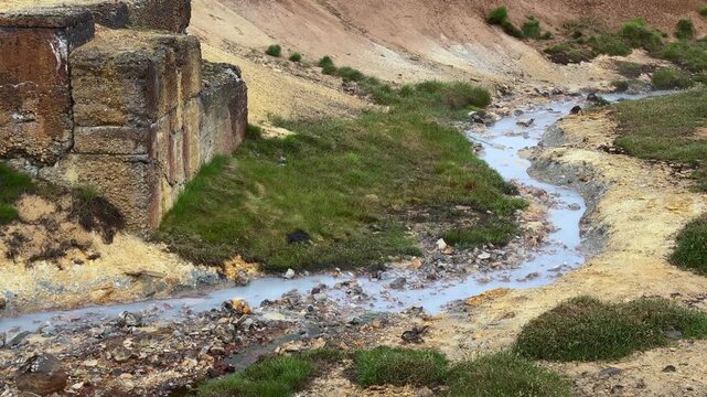 Volcanic landscape at the Seltun geothermal area in Krysuvik, Iceland. Hot spring stream flowing through the colorful sulphuric soil