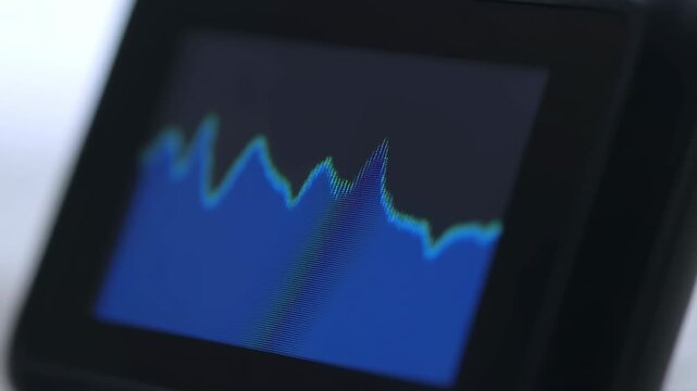 Close-up of a blue line graph on a dark screen