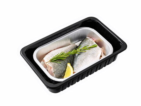 Two fresh whole healthy uncooked dorade on plastic tray , a sprig of aromatic herb and slice of lemon in an overhead view.